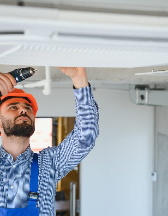 Electrician repairing air conditioner indoors